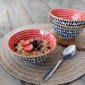 KitchenCraft Red Swirl and Black Spots Ceramic Bowl on a placemat being used for cereal