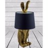Antique Gold Rabbit Ears Lamp With Black Shade on a white wooden surface