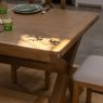 Manor Oak 2m Extending Crossed Leg Dining Table With 4 Cross Back Chairs & Bench close up lifestyle image