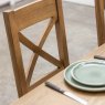 Manor Oak 1.3m Extending Crossed Leg Dining Table With 4 Cross Back Chairs close up lifestyle image